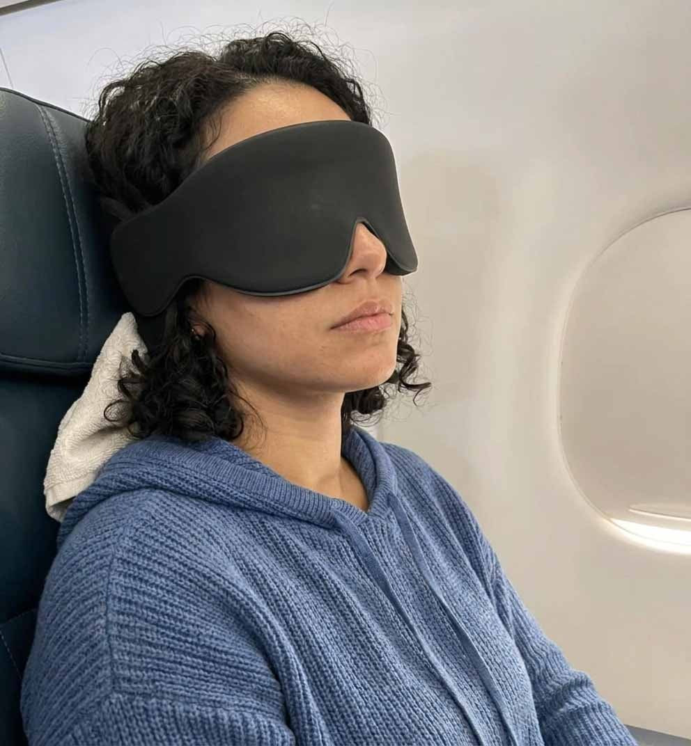 Traveler in a blue hoodie asleep with the JetNod mask