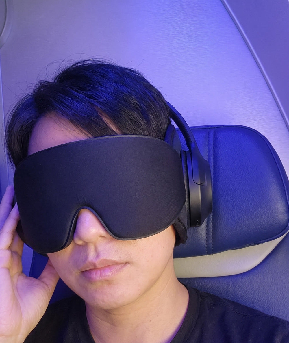 Traveler wearing the JetNod mask with headphones on a night flight